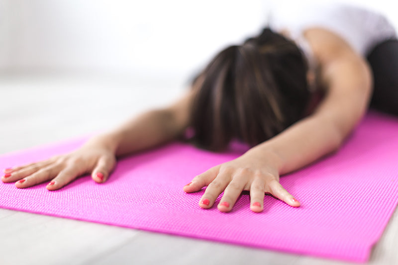 Woman in a face down yoga pose on a pink exercising mat
