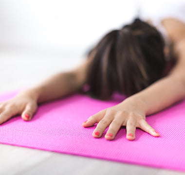 Woman in a face down yoga pose on a pink exercising mat