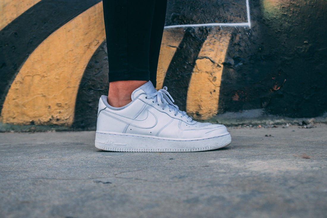 White Nike Sneakers infront of a black and orange wall