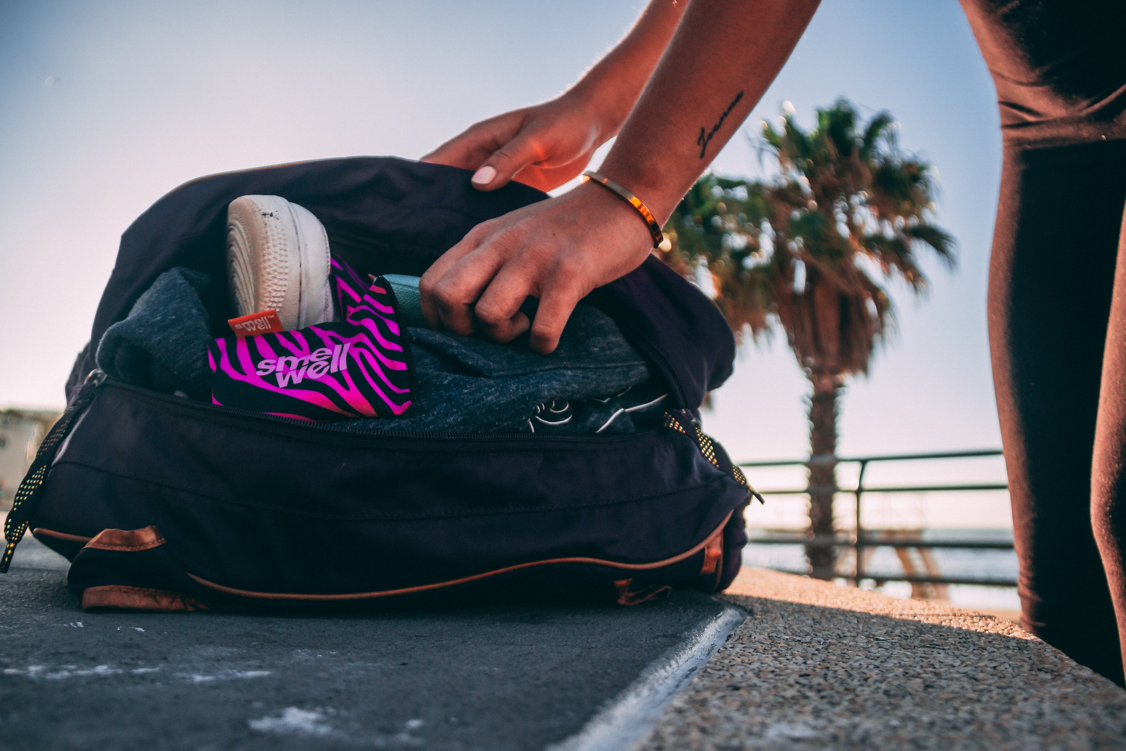 Person packing up a black sports bag with stuff and SmellWell Inserts