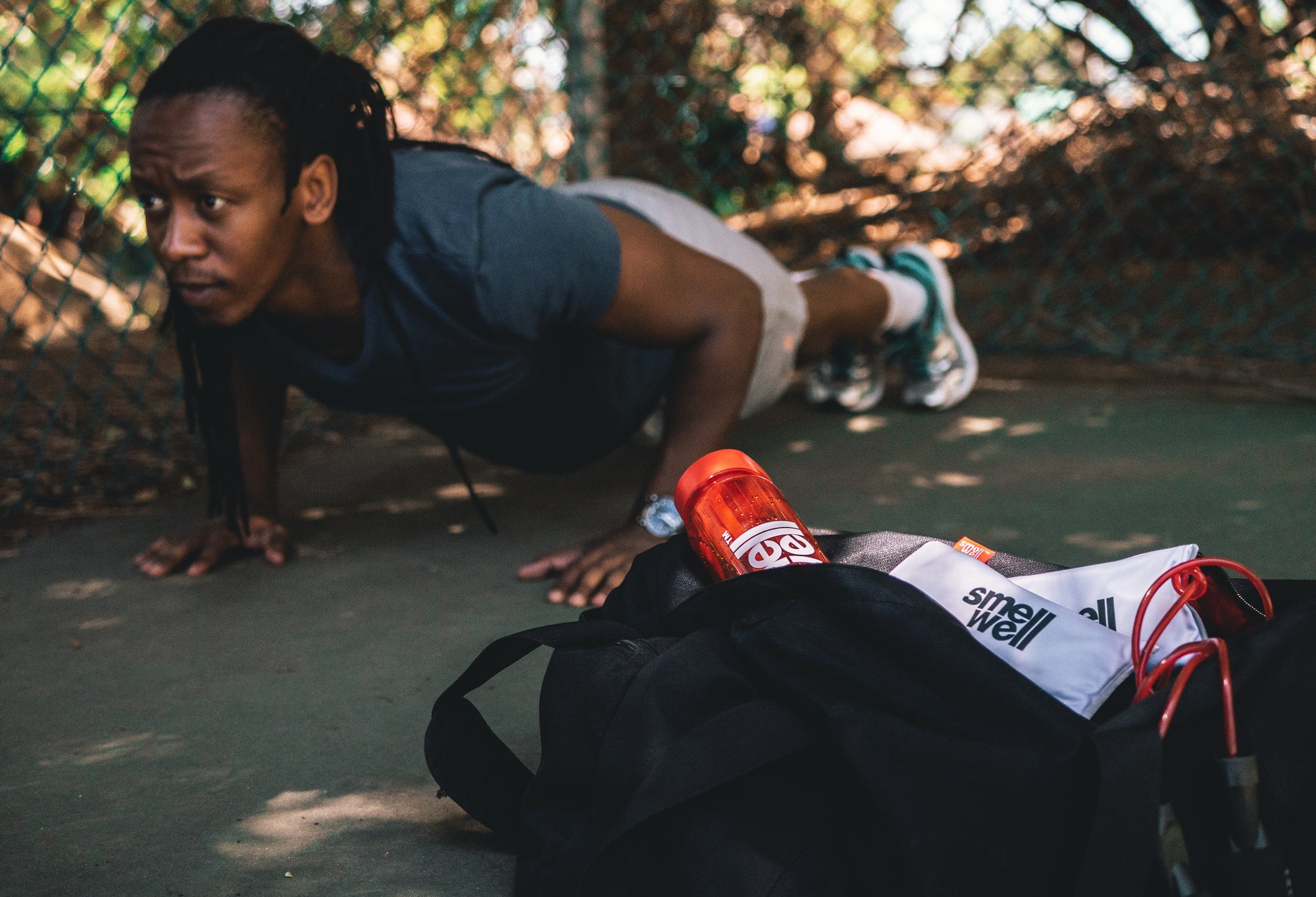 Man doing push ups in the background of a bag with a couple of SmellWell inserts and a bottle in it 