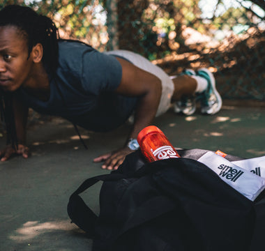 Man doing push ups in the background of a bag with a couple of SmellWell inserts and a bottle in it 
