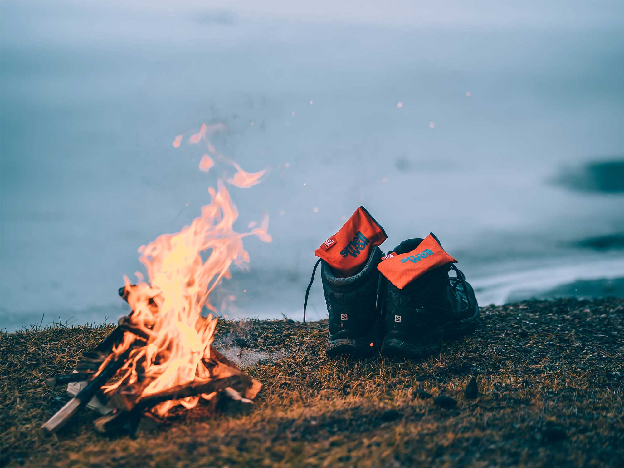 A pair of outdoor shoes with SmellWell Inserts inside them, infront of a fireplace outside