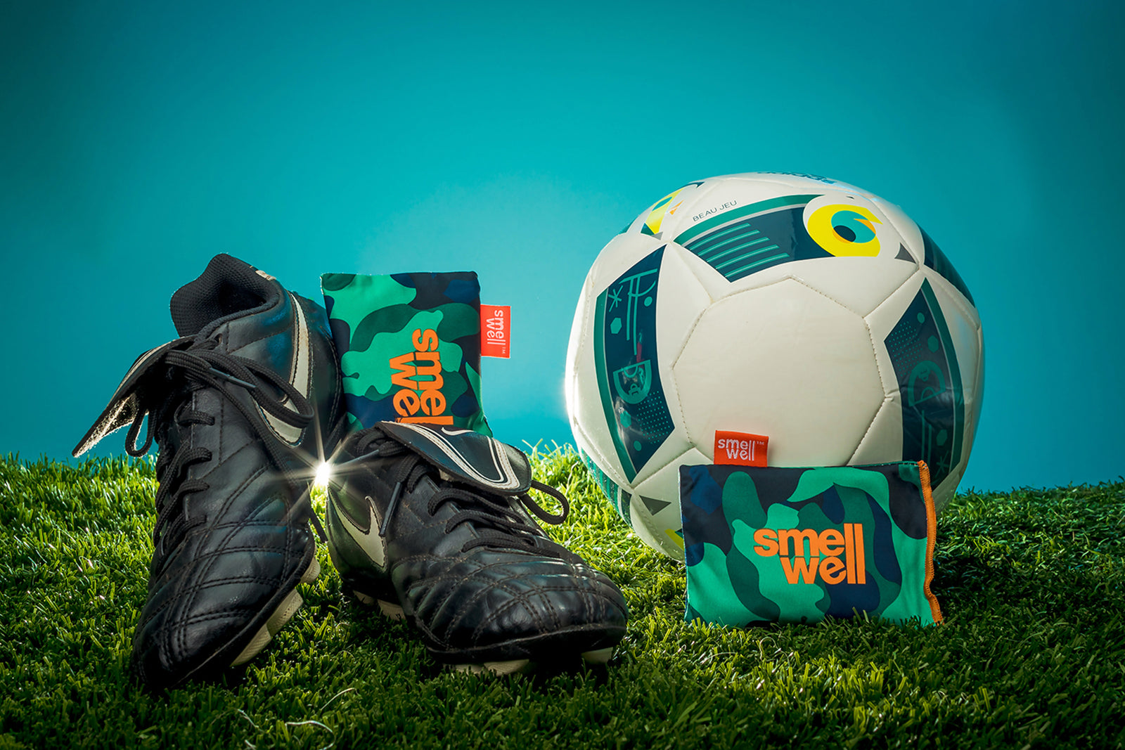 Black Nike football shoes with green SmellWell Actibe Inserts next to a white soccer ball 