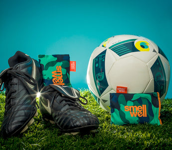 Black Nike football shoes with green SmellWell Actibe Inserts next to a white soccer ball 