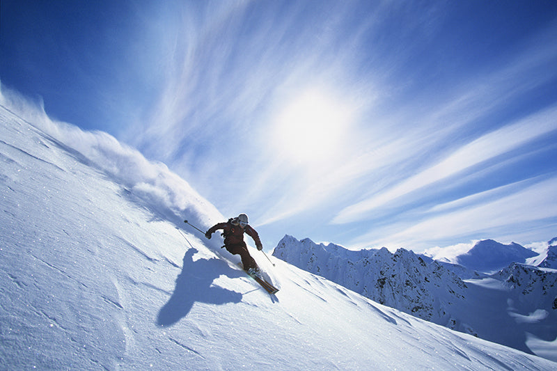 A person skiing down a hill covered with powder snow in the sun