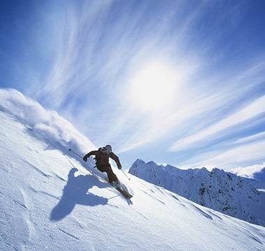A person skiing down a hill covered with powder snow in the sun