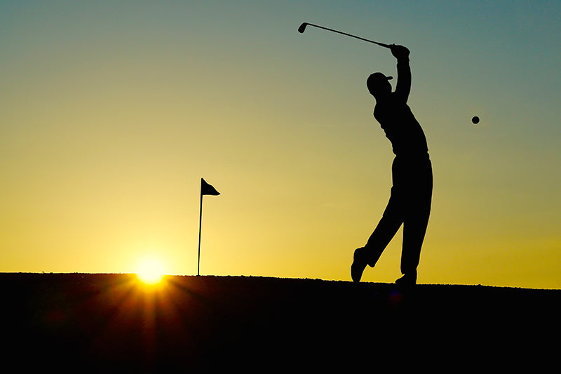 The contours of a person swinging a golf club in the sunset