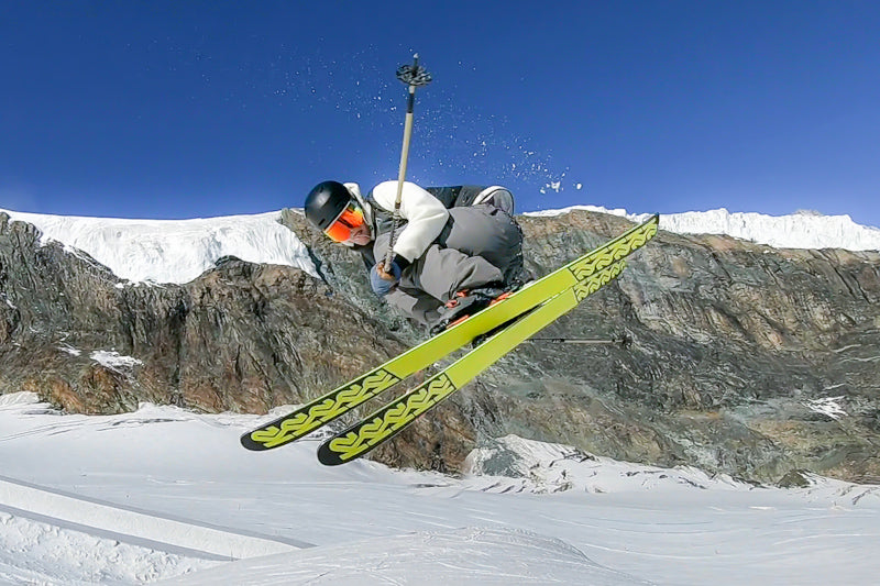 Man on skiis in the middle of a jump doing a spin