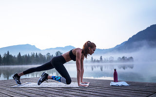 Woman exercising on a mat on a bridge next to the foggy water