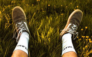 Selfshot image of a mans feet in green grass with yellow flowers