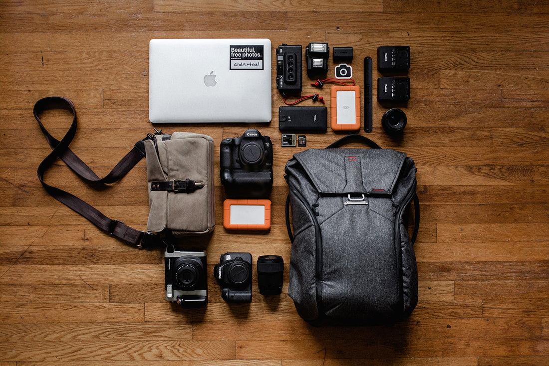 Tophead view of a backpack. Different accessories, such as a laptop and a camera, spread out in a organized grid around it.